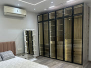 A modern glass wardrobe with built-in lighting, mirrored doors, and a wooden finish.